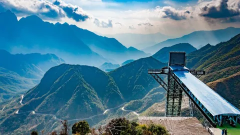 Sapa Glass Bridge extending over a mountain pass with clouds and distant peaks