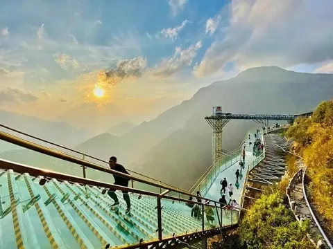 Sapa Glass Bridge extending over a mountain pass with clouds and distant peaks