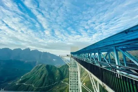 Sapa Glass Bridge extending over a mountain pass with clouds and distant peaks