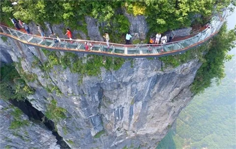Sapa Glass Bridge extending over a mountain pass with clouds and distant peaks