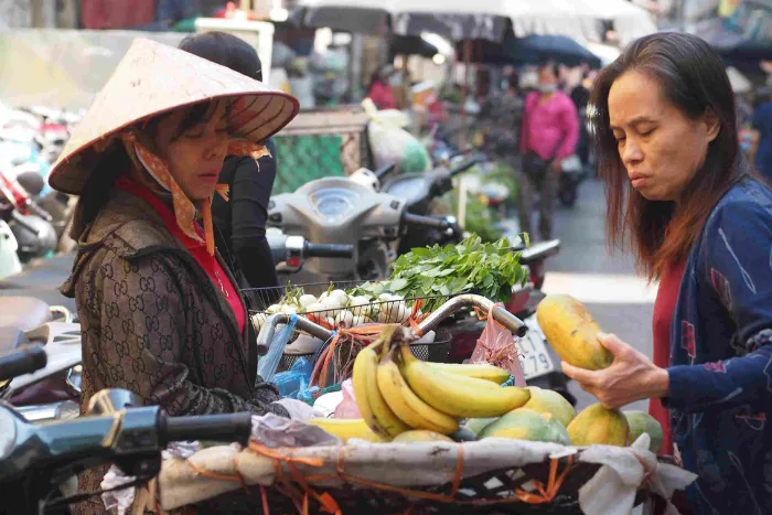 Shopper haggling with a vendor at a busy Vietnamese market