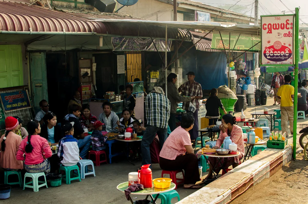 Interior of a Burmese tea shop with low tables and tea cups