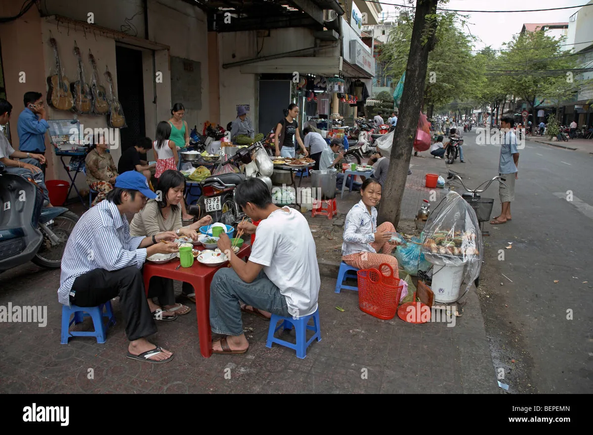 Crowded street food stall with locals eating at low plastic tables