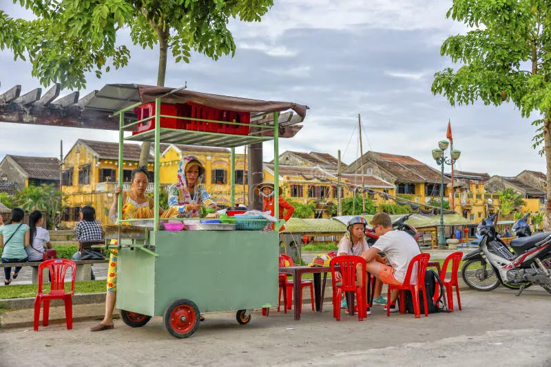 Crowded street food stall with locals eating at low plastic tables
