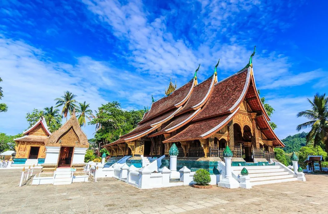 Panoramic view of Luang Prabang, Laos, with the Mekong River, ancient temples, and lush mountains at sunset.