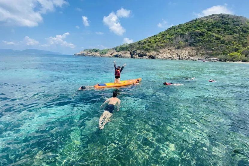Panoramic view of Con Dao's pristine coastline with lush green mountains, turquoise waters, and traditional fishing boats