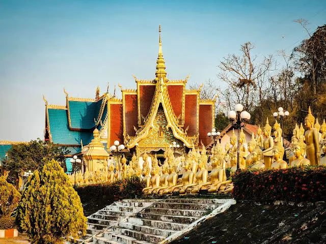 Panoramic view of Pakse city and the Mekong River at sunset, with traditional Lao boats and lush green hills
