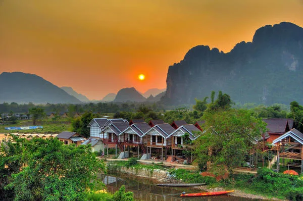 Panoramic view of Vang Vieng, Laos, featuring the Nam Song River winding through lush green rice fields and towering limeston