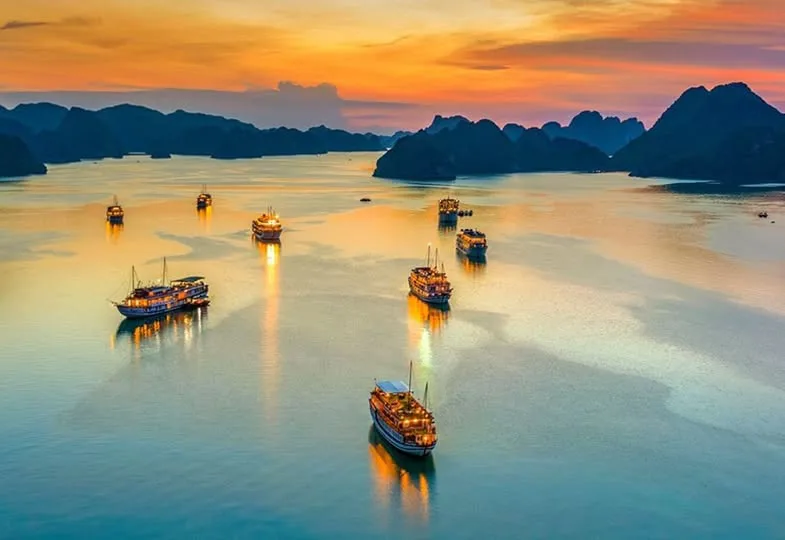 Panoramic view of Ha Long Bay limestone karsts and a traditional junk boat.